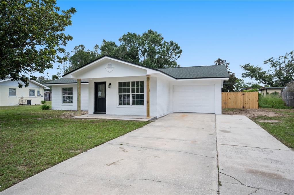 A white brick single-story house with a black front door and a concrete driveway — 4052 LANA DRIVE, LAKELAND, FL