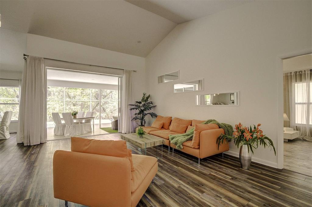 A living room features orange sofas, wood-look flooring, and a sliding glass door to a patio — 14 CARNATION COURT, HOMOSASSA, FL
