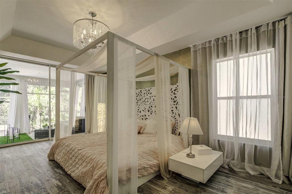 A bedroom features a four-poster bed, a crystal chandelier, and a sliding glass door — 14 CARNATION COURT, HOMOSASSA, FL