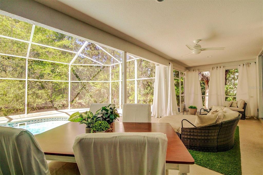A screened-in patio features a dining table, lounge seating, and a view of a pool — 14 CARNATION COURT, HOMOSASSA, FL
