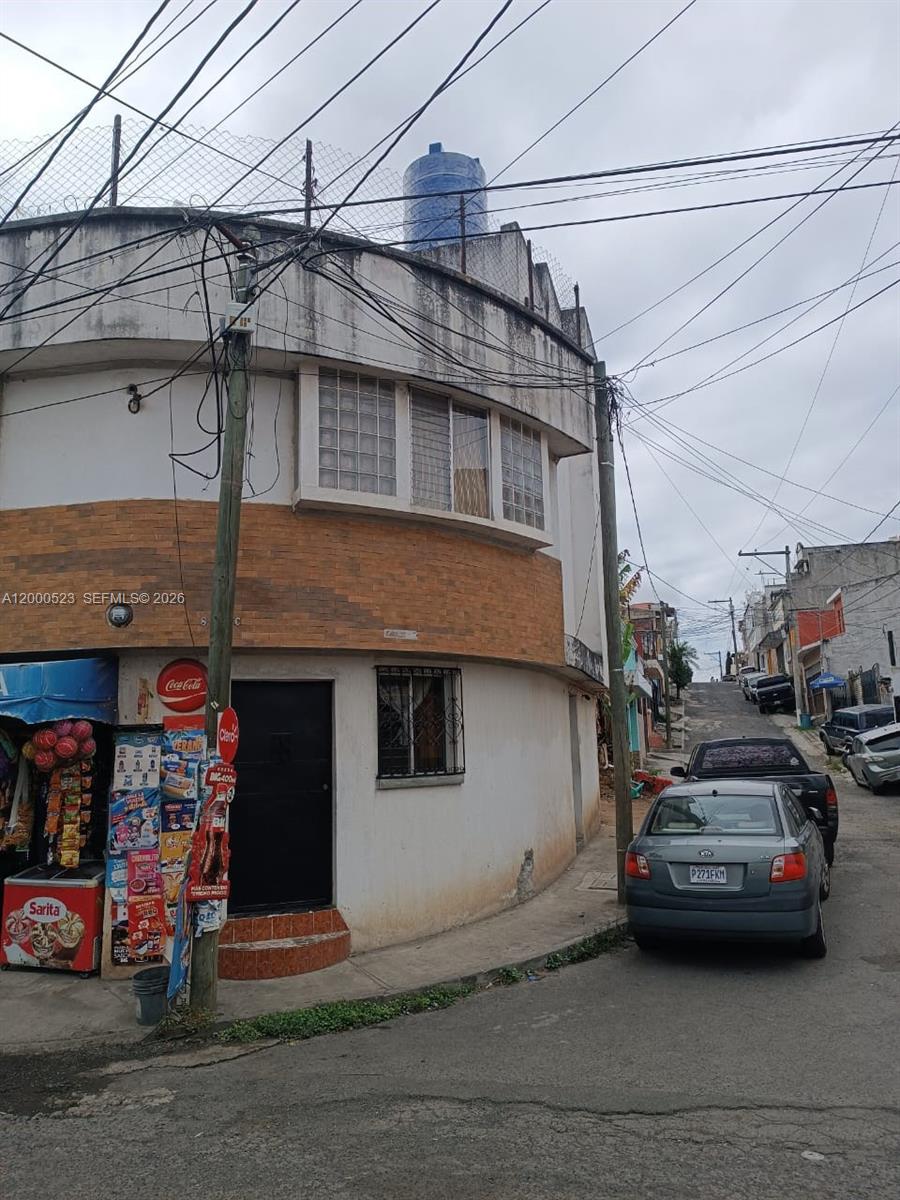 A two-story corner building with a small storefront, brick facade, and a rooftop water tank — 9 calle NW 8-92 zona 11, MA 01057, MA