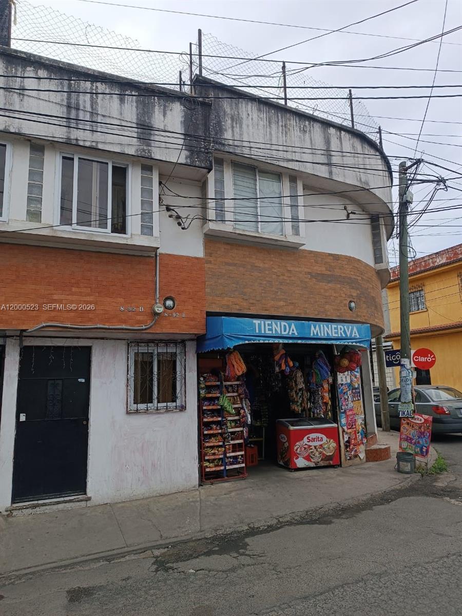 A two-story building features a ground-level convenience store named Tienda Minerva under a blue awning — 9 calle NW 8-92 zona 11, MA 01057, MA