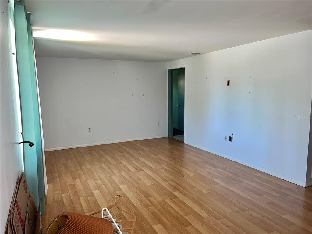 An empty room with light wood-look flooring, white walls, and a doorway leading elsewhere — 503 S VENICE BOULEVARD, VENICE, FL