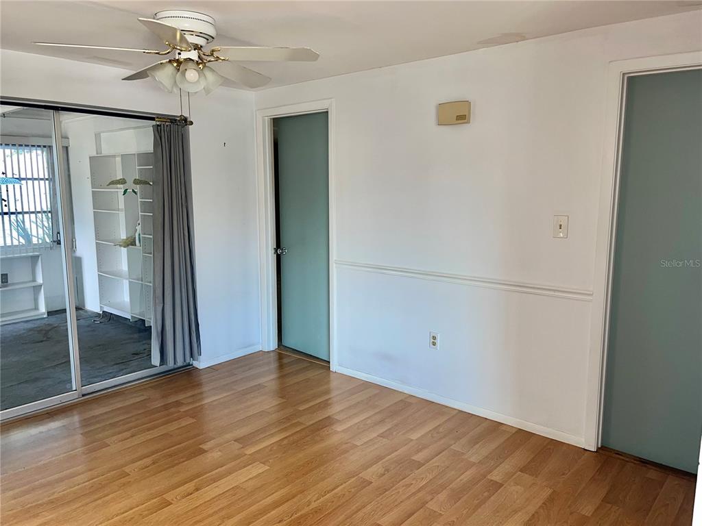 A room with wood-look flooring, a ceiling fan, two doors, and a sliding glass door — 503 S VENICE BOULEVARD, VENICE, FL