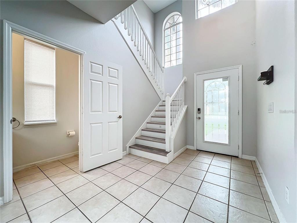 An entryway features a tiled floor, a staircase with white railings, and a front door — 5356 WATERVISTA DRIVE, ORLANDO, FL