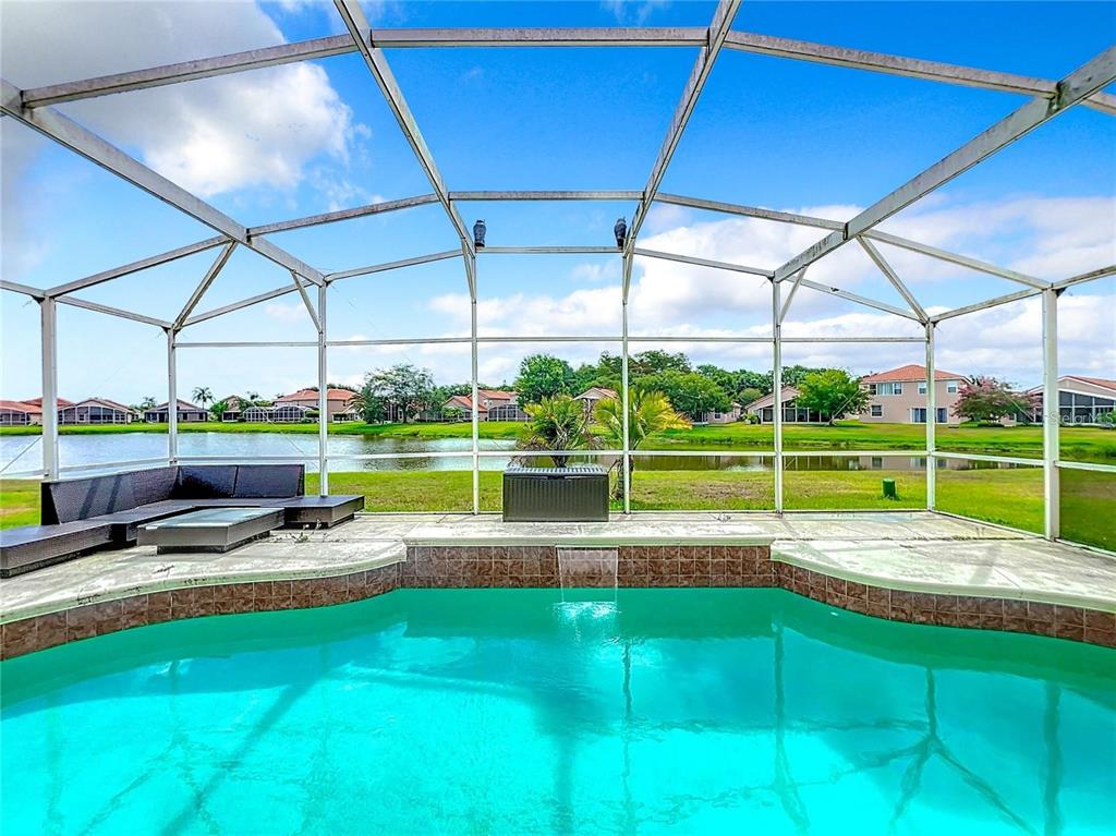 A screened-in pool patio overlooks a lake and neighboring houses on a sunny day — 5356 WATERVISTA DRIVE, ORLANDO, FL