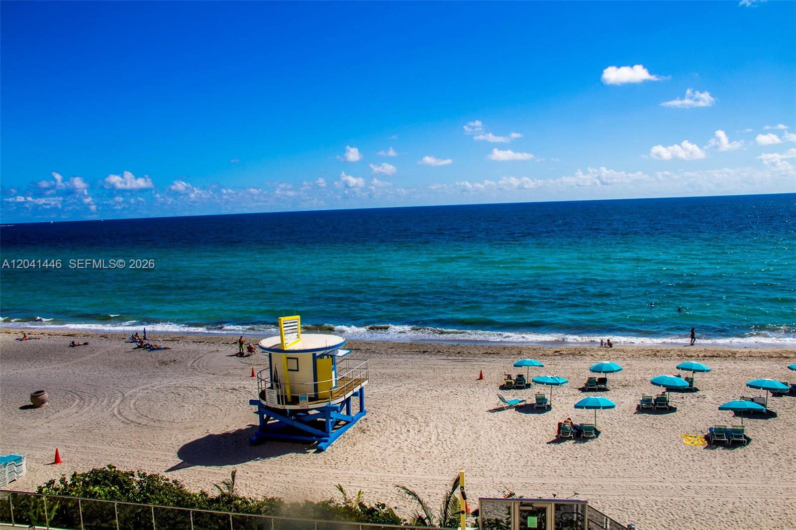 A yellow and blue lifeguard tower stands on a sandy beach by the ocean — 2501 S Ocean Dr # 327, Hollywood FL 33019, HOLLYWOOD, FL