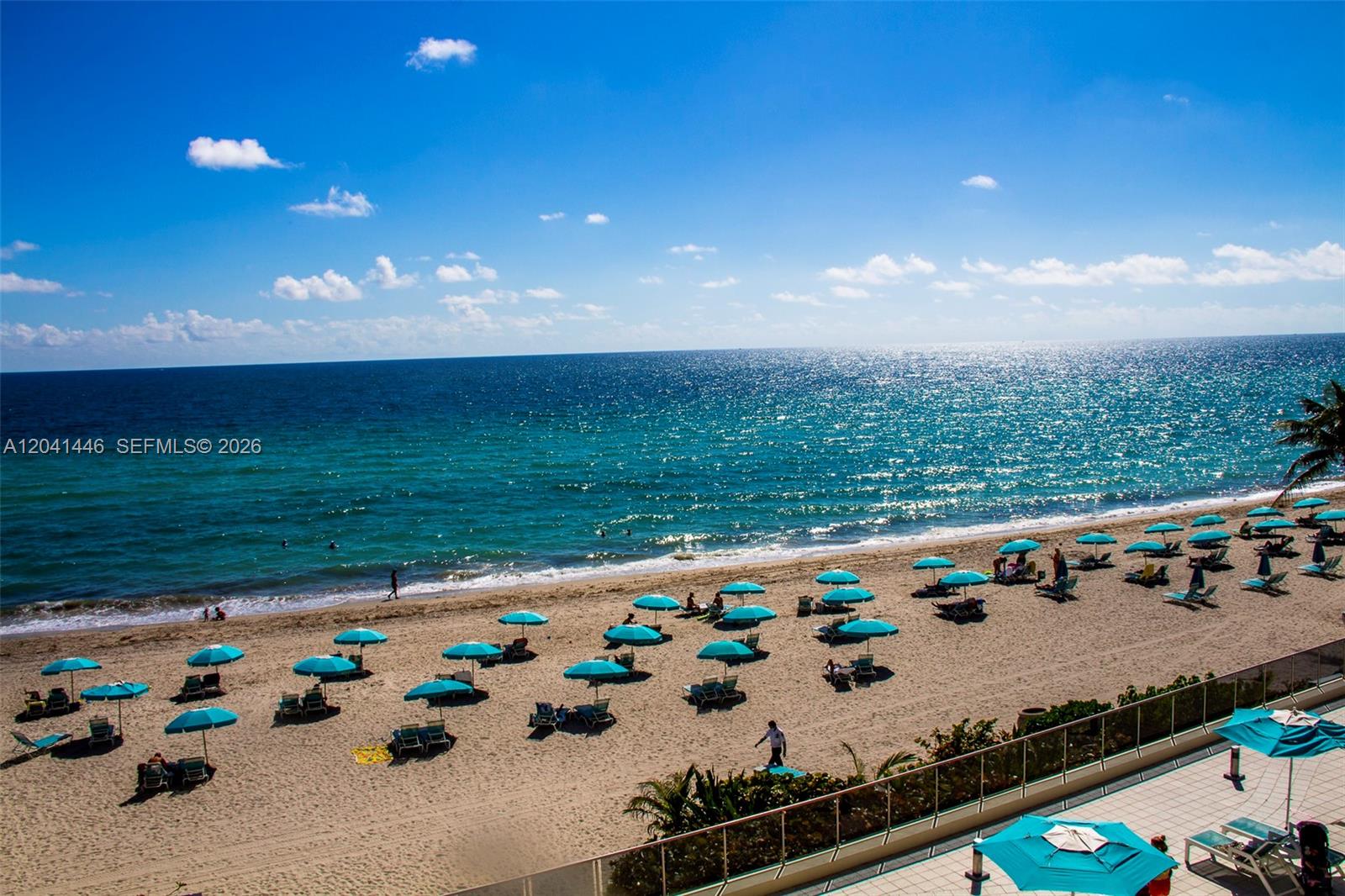 A high-angle view shows a sandy beach with numerous blue umbrellas and lounge chairs — 2501 S Ocean Dr # 327, Hollywood FL 33019, HOLLYWOOD, FL