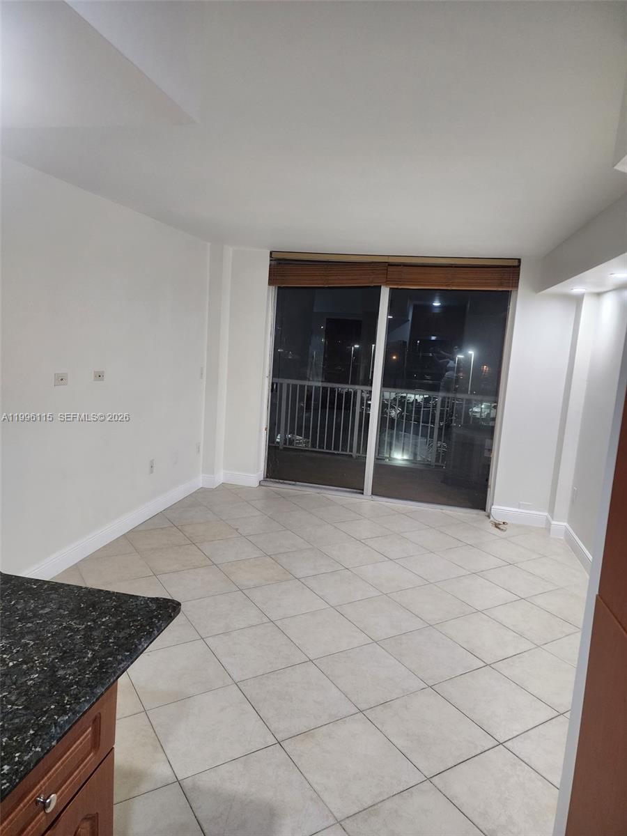 An empty room with light-colored tile flooring and a sliding glass door to a balcony — 1800 NW 24th Ave # 415, Miami FL 33125, MIAMI, FL