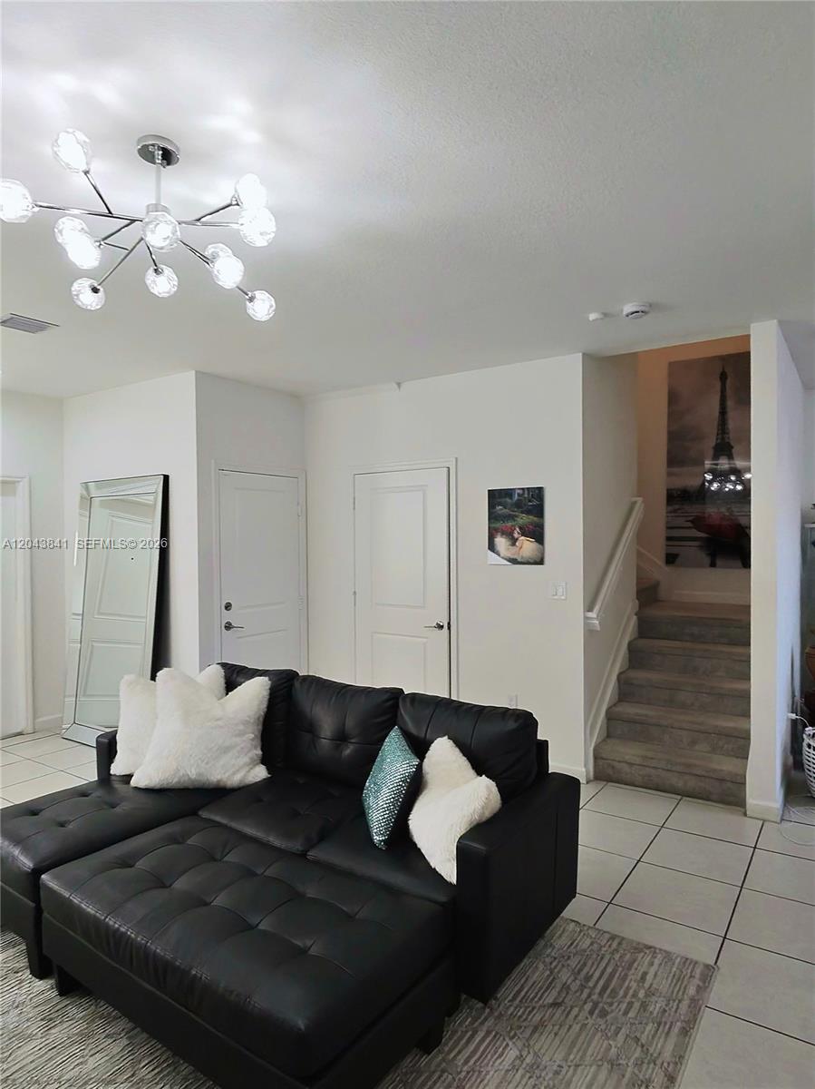 A living room features a black sectional sofa, a modern chandelier, and stairs leading upward — 23013 SW 128th Pl, Miami FL 33170, MIAMI, FL