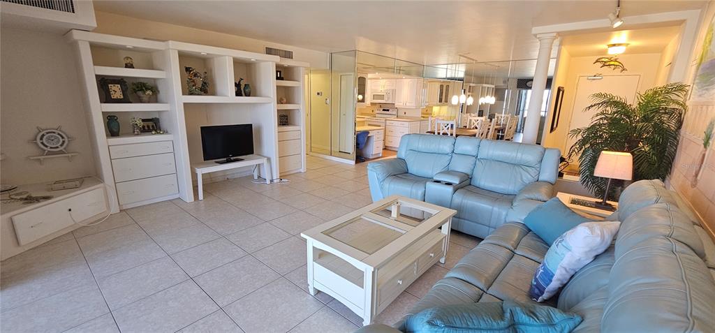 A living room features light blue leather sofas, a white coffee table, and built-in shelving — 10355 PARADISE BOULEVARD UNIT 710, TREASURE ISLAND, FL