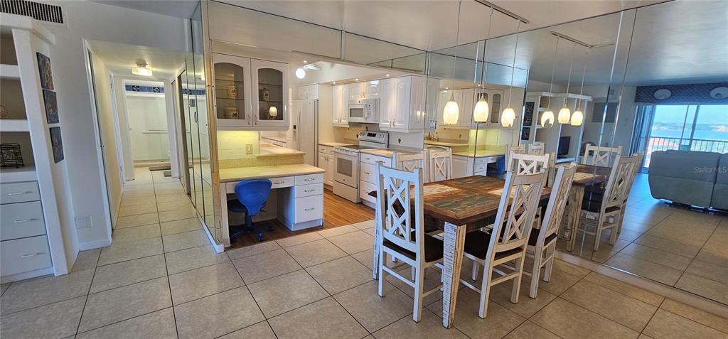 A kitchen with white cabinets and a dining area featuring mirrored walls and tile flooring — 10355 PARADISE BOULEVARD UNIT 710, TREASURE ISLAND, FL
