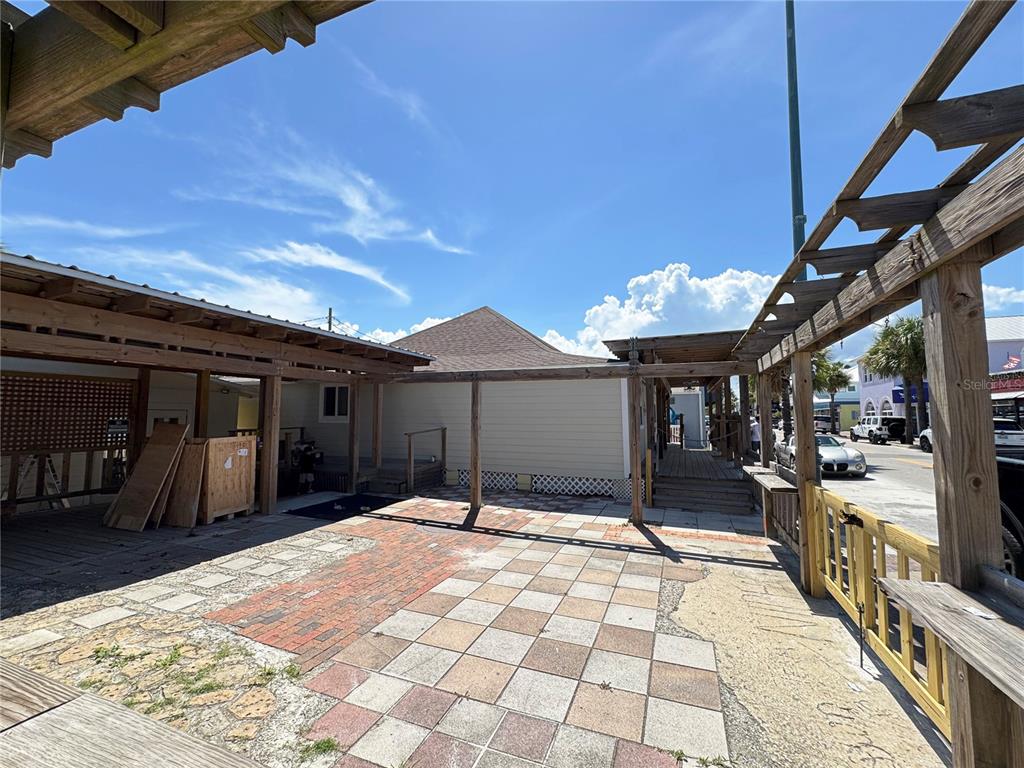 An outdoor patio area features a tiled floor, wooden pergola structures, and a nearby building — 411 FLAGLER AVENUE, NEW SMYRNA BEACH, FL