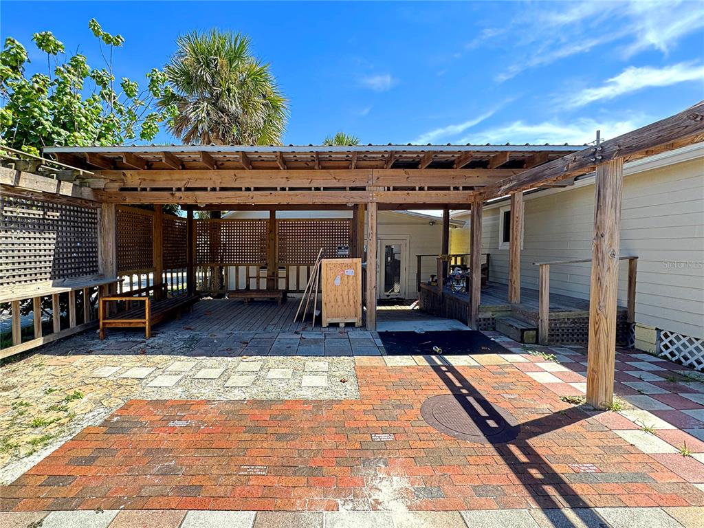 A covered wooden patio area features a brick-paved ground and lattice privacy screens — 411 FLAGLER AVENUE, NEW SMYRNA BEACH, FL
