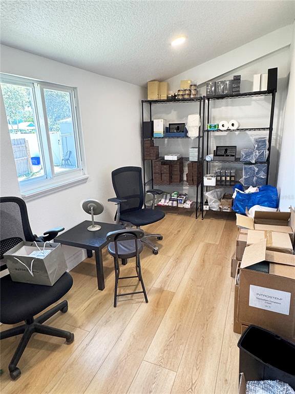 A small office room features light wood-look flooring, two metal storage shelves, and office chairs — 411 FLAGLER AVENUE, NEW SMYRNA BEACH, FL