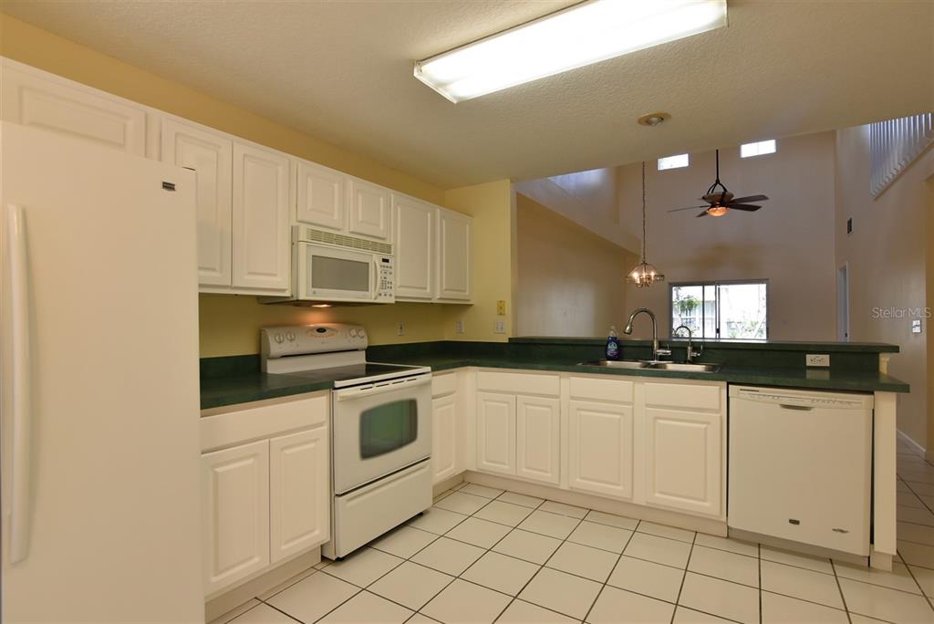 A kitchen with white cabinets, green countertops, white appliances, and tiled flooring — 2203 CYPRESS KNEE LOOP, KISSIMMEE, FL
