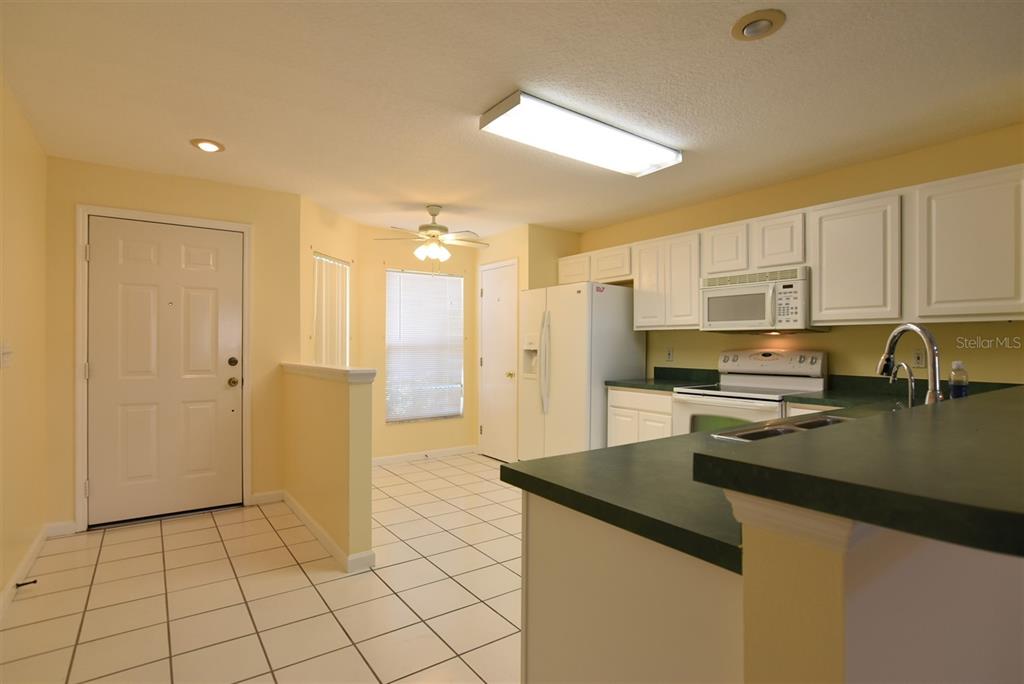 A kitchen with white cabinets, green countertops, and a tiled floor next to an entryway — 2203 CYPRESS KNEE LOOP, KISSIMMEE, FL