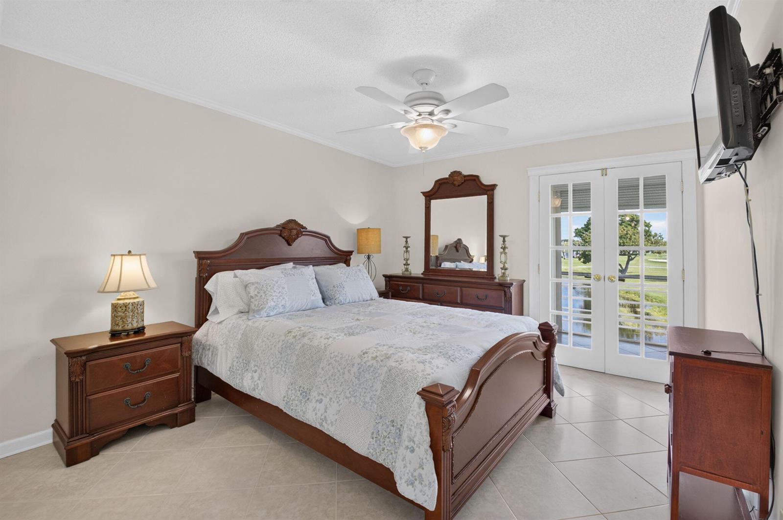 A bedroom features a wooden bed frame, matching furniture, a ceiling fan, and glass doors — 323 Capri G # 323, Delray Beach FL 33484, DELRAY BEACH, FL