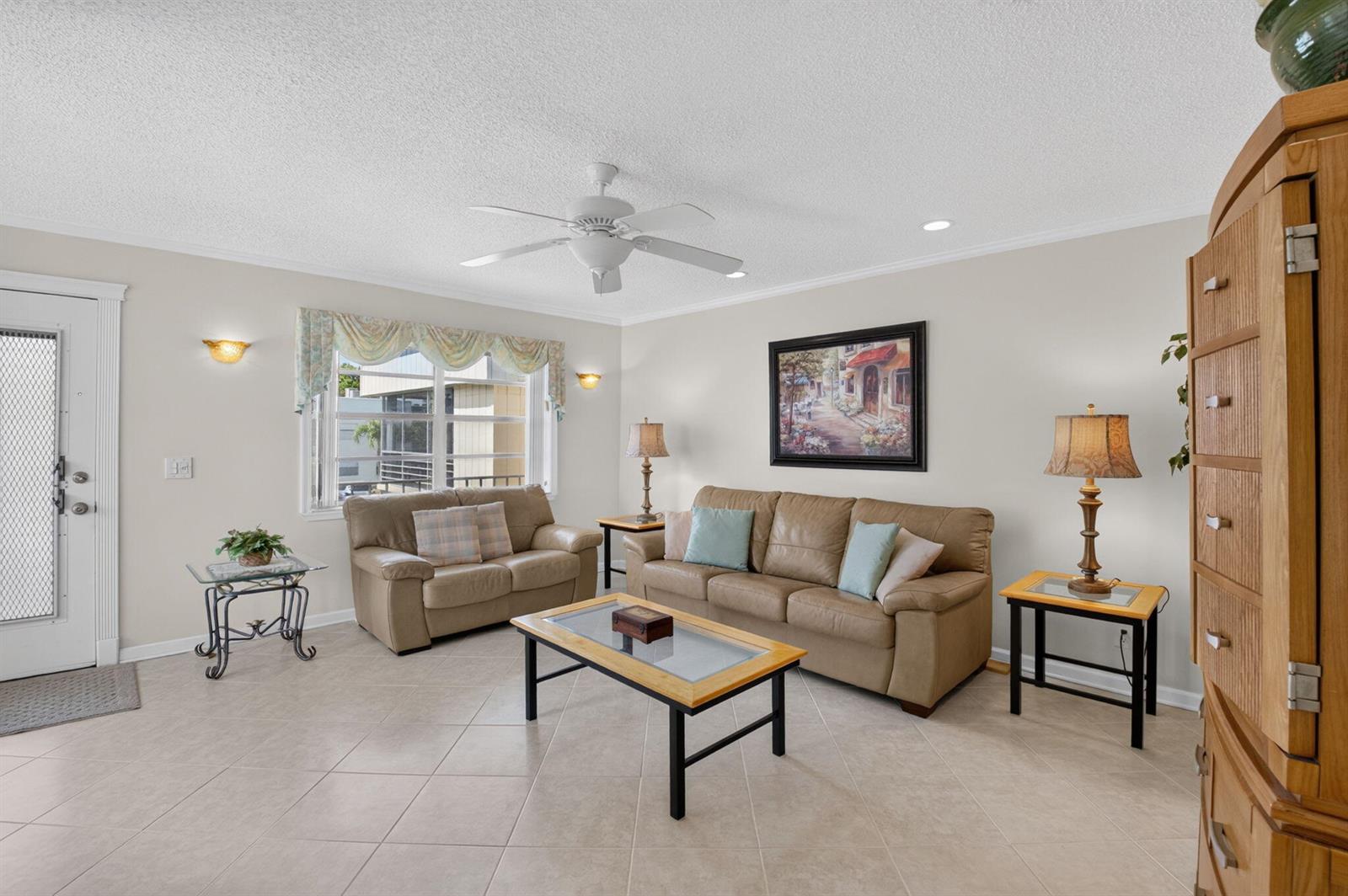 A living room features beige tile floors, two tan sofas, a coffee table, and ceiling fan — 323 Capri G # 323, Delray Beach FL 33484, DELRAY BEACH, FL