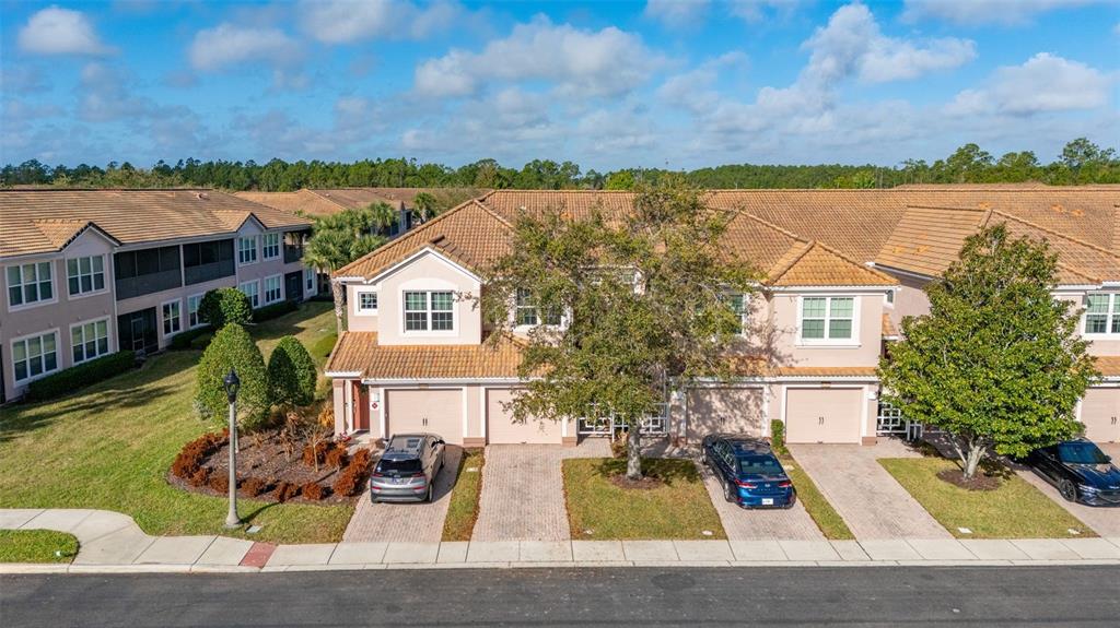 An aerial view of a multi-unit residential building with beige stucco, tile roofs, and driveways — 1256 ROMANI AVENUE, DAVENPORT, FL