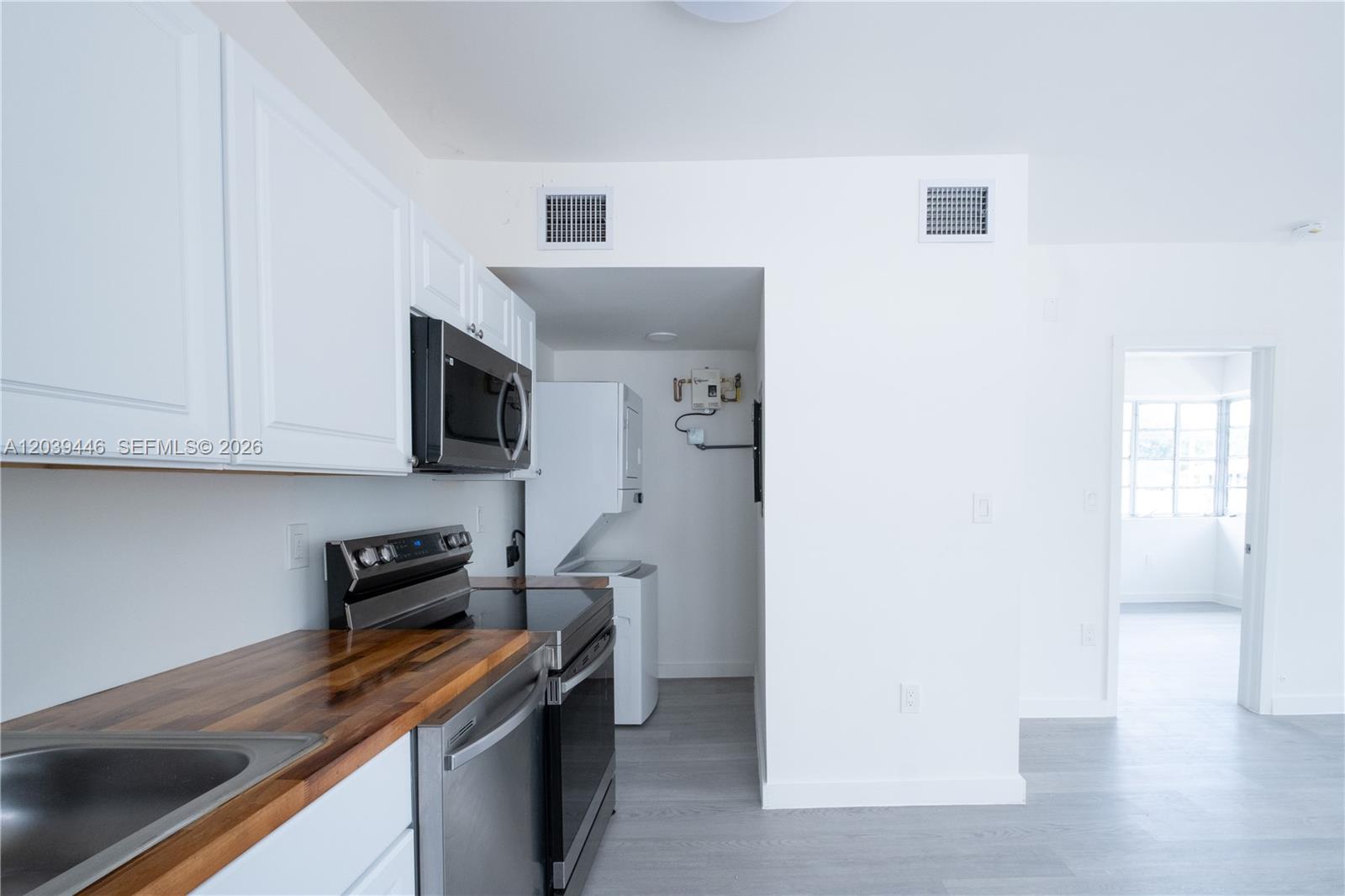 A kitchen features white cabinets, wood countertops, stainless steel appliances, and an adjacent laundry area — 423 NE 71st St # 4, Miami FL 33138, MIAMI, FL