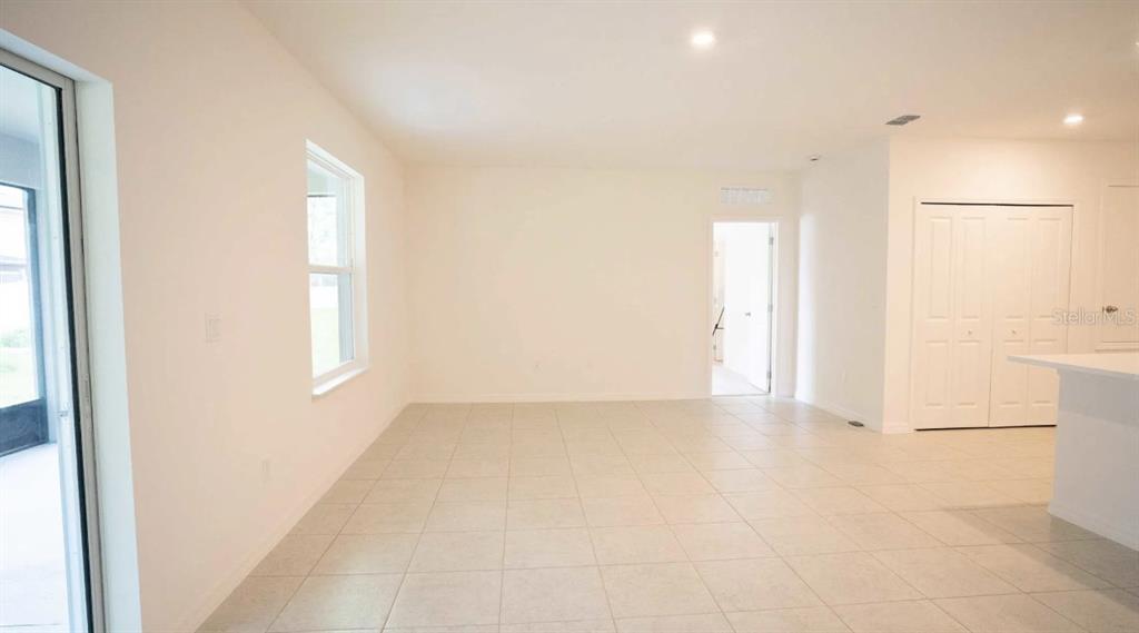 An open-concept room features light-colored tile flooring, white walls, a window, and a doorway — TBD SW 80TH WAY, GAINESVILLE, FL