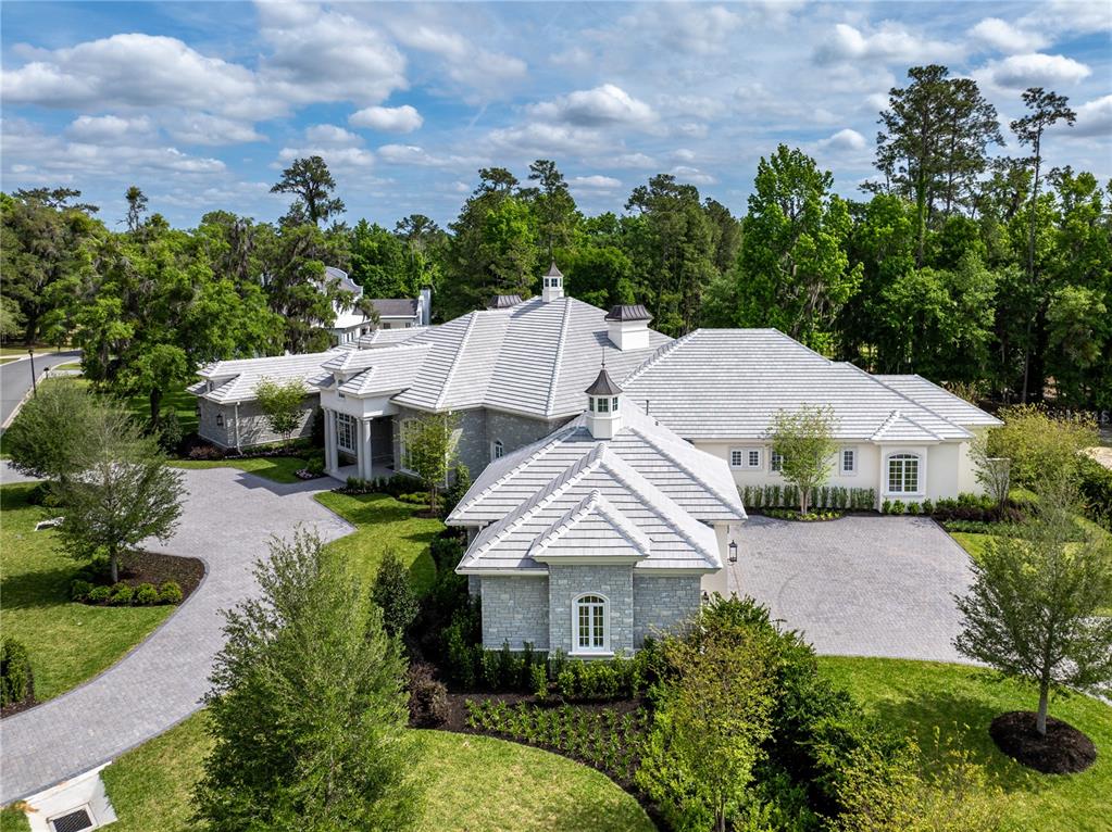 An aerial view shows a large stone house with a white tile roof and driveway — 8707 NW 31ST LANE ROAD, OCALA, FL
