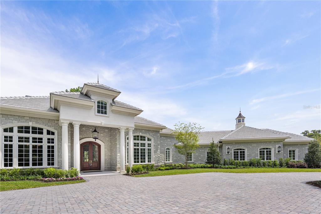 A single-story stone house with a paved driveway, white columns, and a cupola roof — 8707 NW 31ST LANE ROAD, OCALA, FL