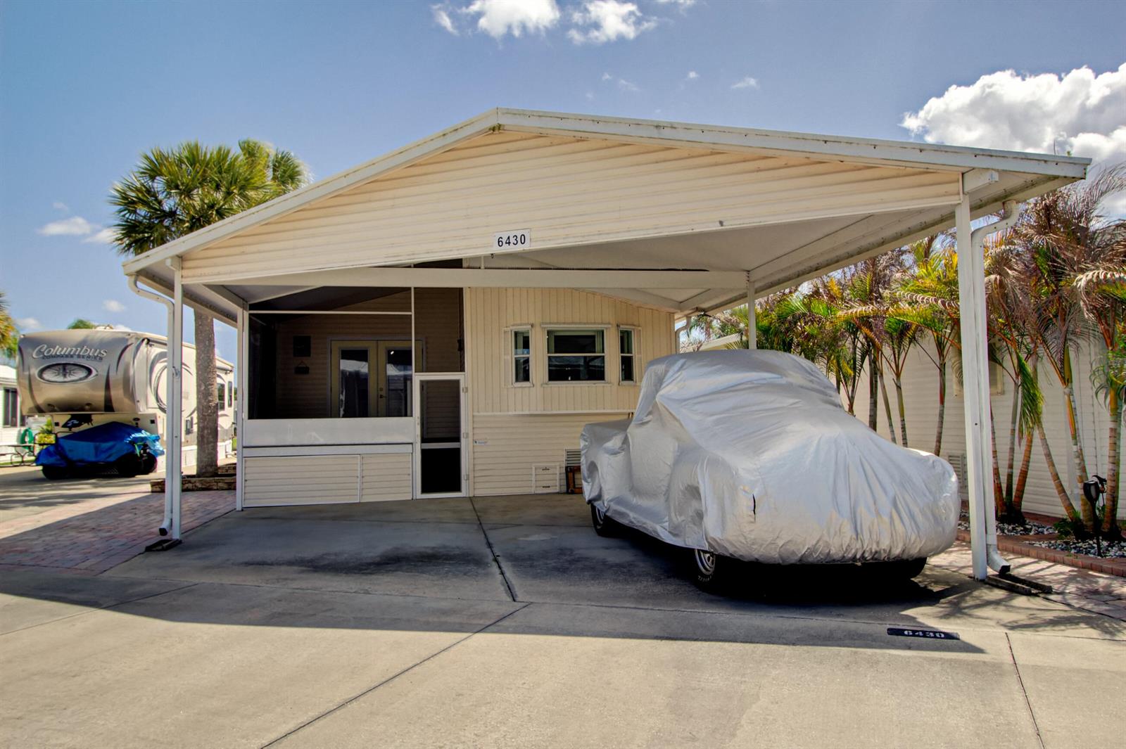 A mobile home features a large carport, a screened-in porch, and a vehicle under a cover — 6430 SE 51st Street, Okeechobee FL 34974, OKEECHOBEE, FL