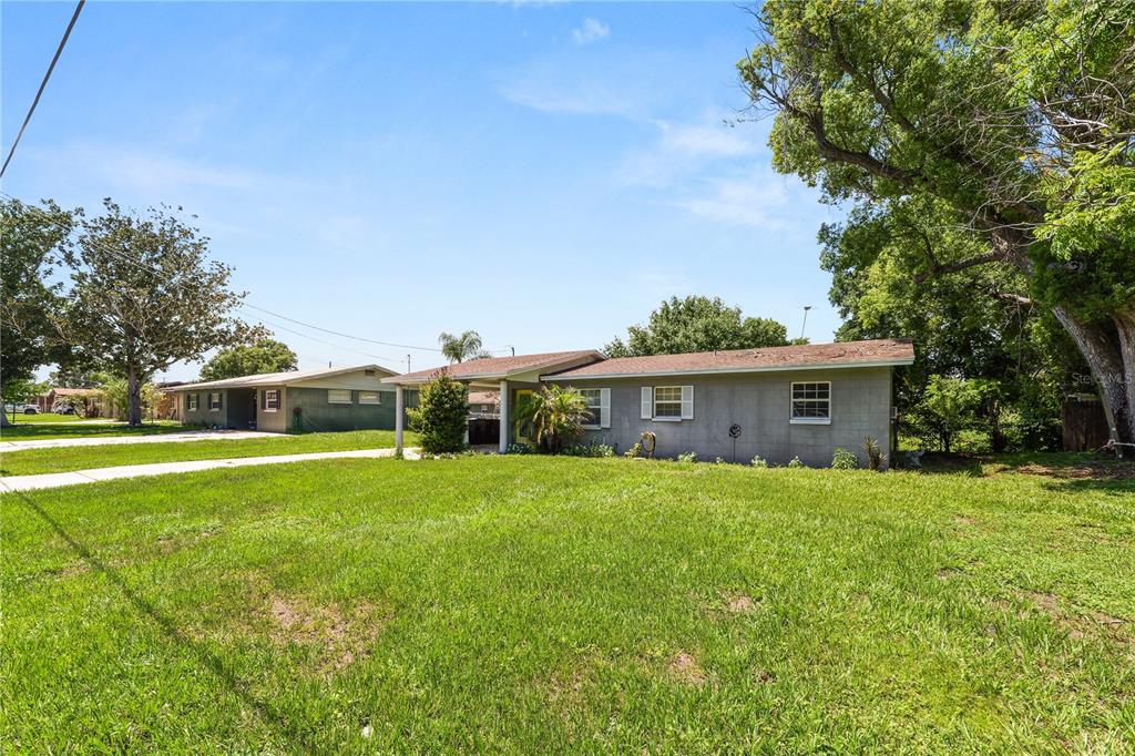 A single-story concrete block house with a carport sits on a large grassy lot — 517 TANGLEWOOD DRIVE, AUBURNDALE, FL