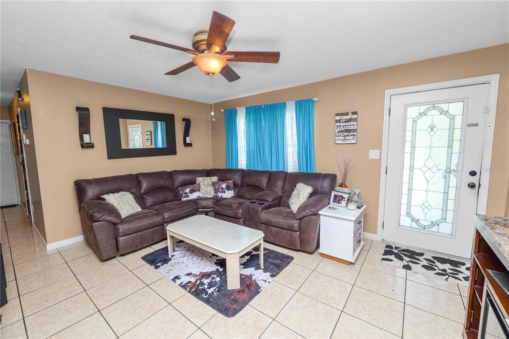 A living room features a brown sectional sofa, a coffee table, and a ceiling fan — 517 TANGLEWOOD DRIVE, AUBURNDALE, FL