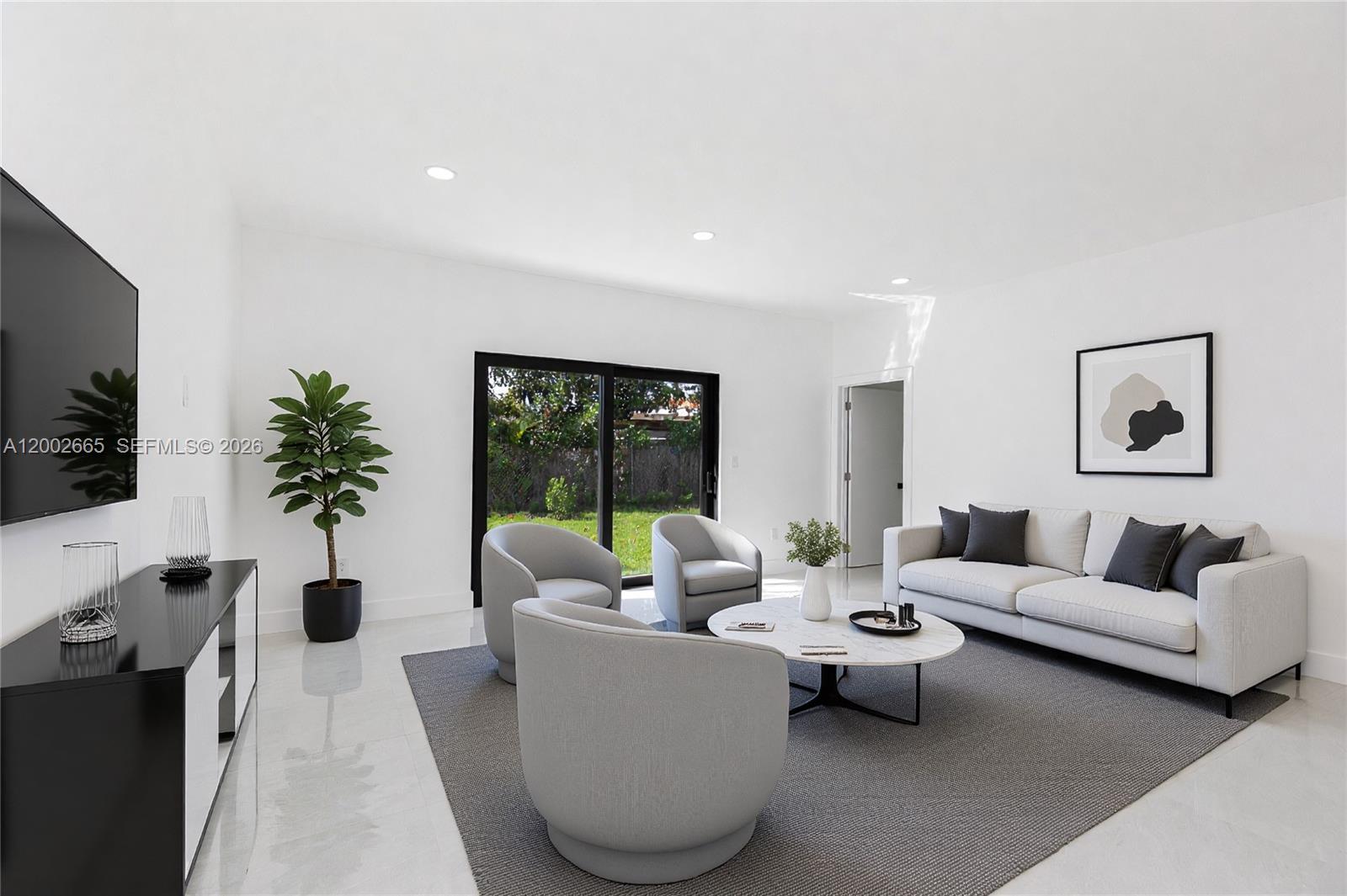 A modern living room features white walls, a gray area rug, and a sliding glass door — 5550 SW 4th St, Miami FL 33134, MIAMI, FL