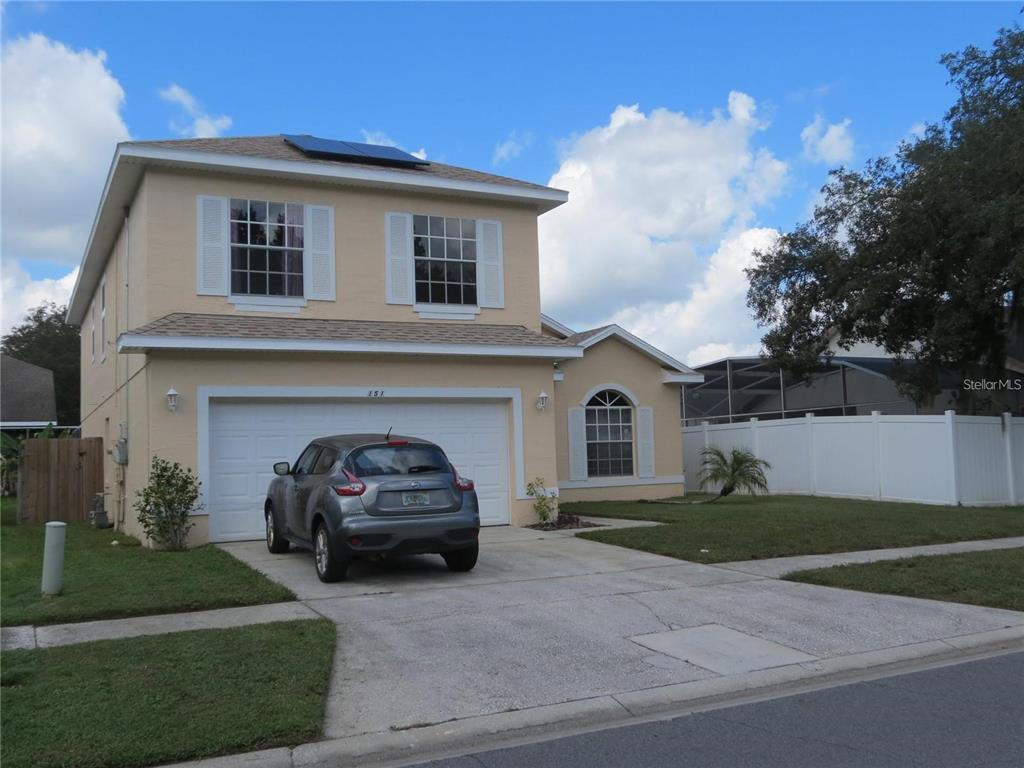 A two-story yellow house with a two-car garage and a concrete driveway at dusk — 151 PINEWOOD DRIVE, DAVENPORT, FL