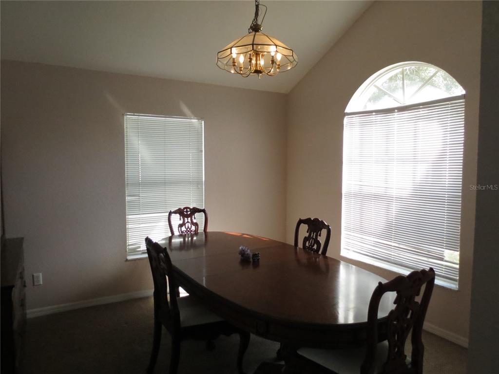 A swimming pool and attached spa are enclosed within a screened lanai at sunset — 151 PINEWOOD DRIVE, DAVENPORT, FL