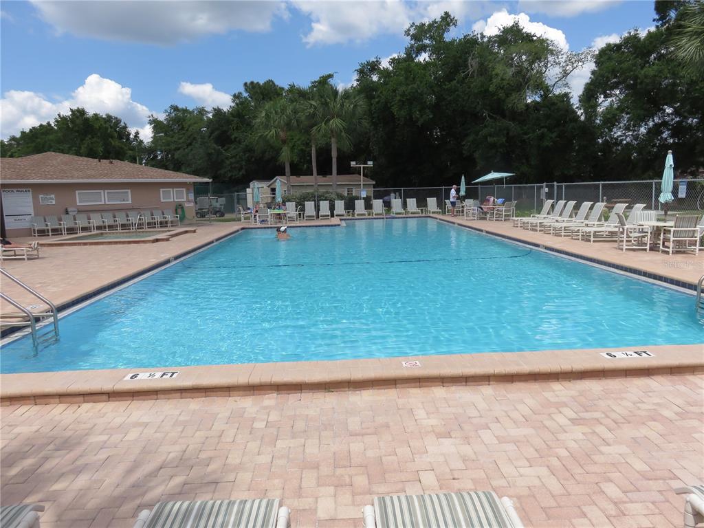 An outdoor rectangular swimming pool is surrounded by a paver deck and lounge chairs — 6440 SPRING FLOWER DRIVE UNIT 12, NEW PORT RICHEY, FL