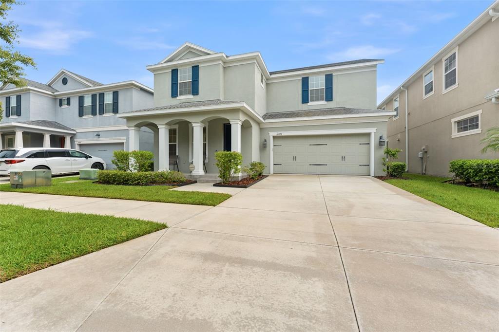A two-story suburban house with a light green exterior, a covered porch, and a garage — 14722 ROCKY BROOK DRIVE, TAMPA, FL