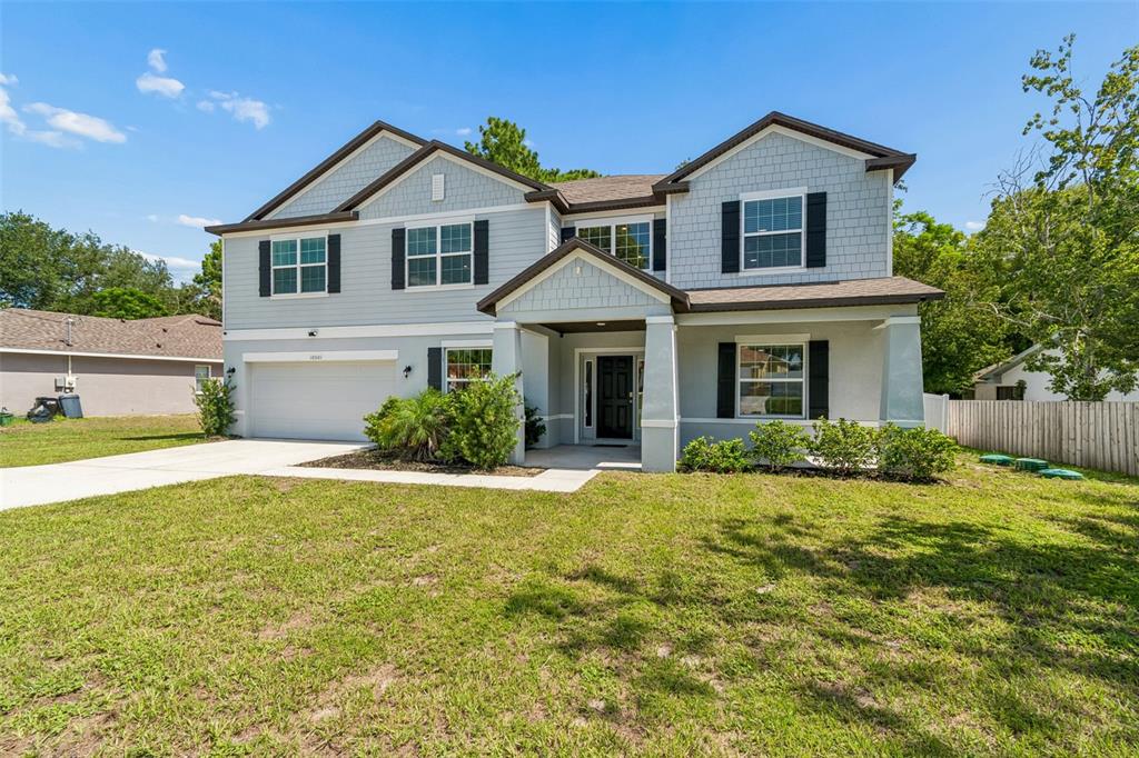 A two-story suburban house with light blue siding, a two-car garage, and a front porch — 10501 RED COACH STREET, SPRING HILL, FL