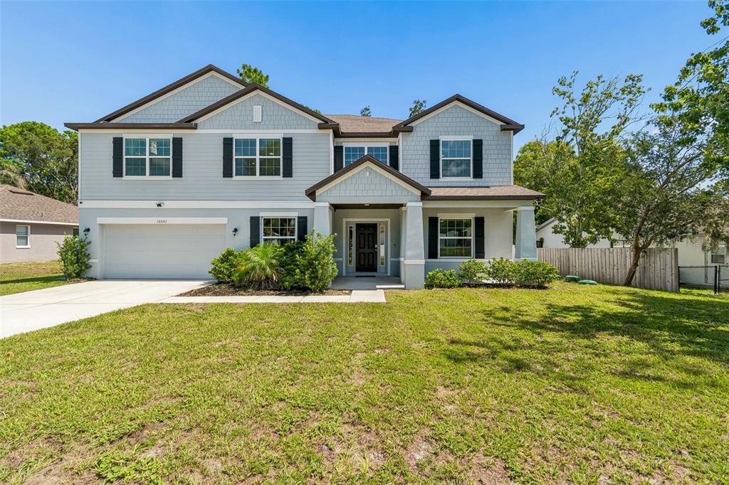 A two-story house with light blue siding, a two-car garage, and a covered front porch — 10501 RED COACH STREET, SPRING HILL, FL