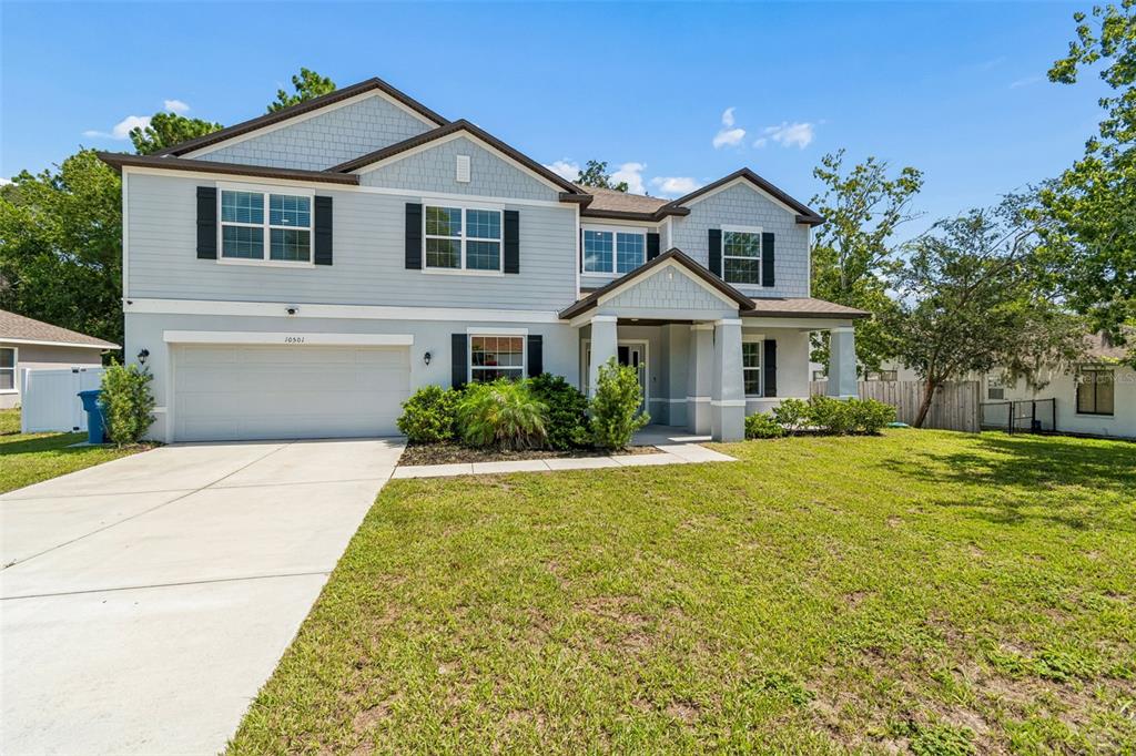 A two-story house with light blue siding, a two-car garage, and a front porch — 10501 RED COACH STREET, SPRING HILL, FL