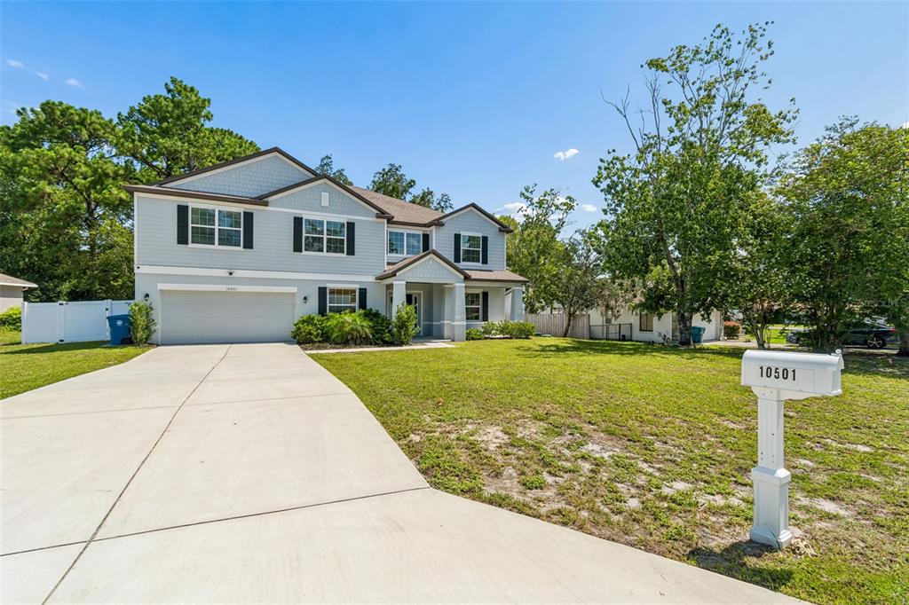 A two-story light blue house with a concrete driveway and a white mailbox — 10501 RED COACH STREET, SPRING HILL, FL