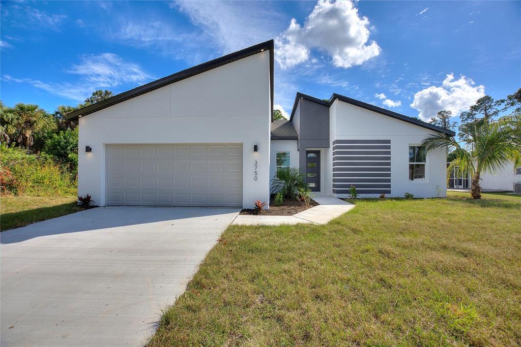 A modern single-story house with a white exterior, gray garage door, and a concrete driveway — 3707 FONTAINEBLEAU STREET, NORTH PORT, FL