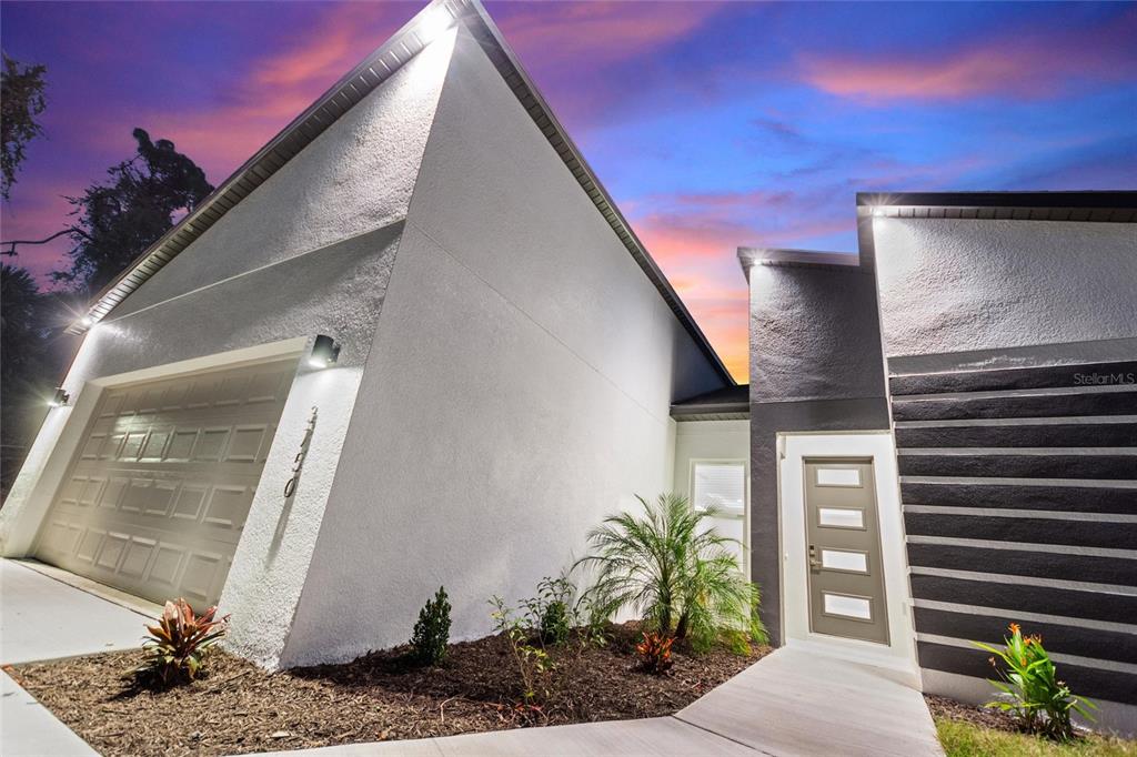 A modern house exterior features a white stucco wall, a garage, and a front entrance — 3707 FONTAINEBLEAU STREET, NORTH PORT, FL