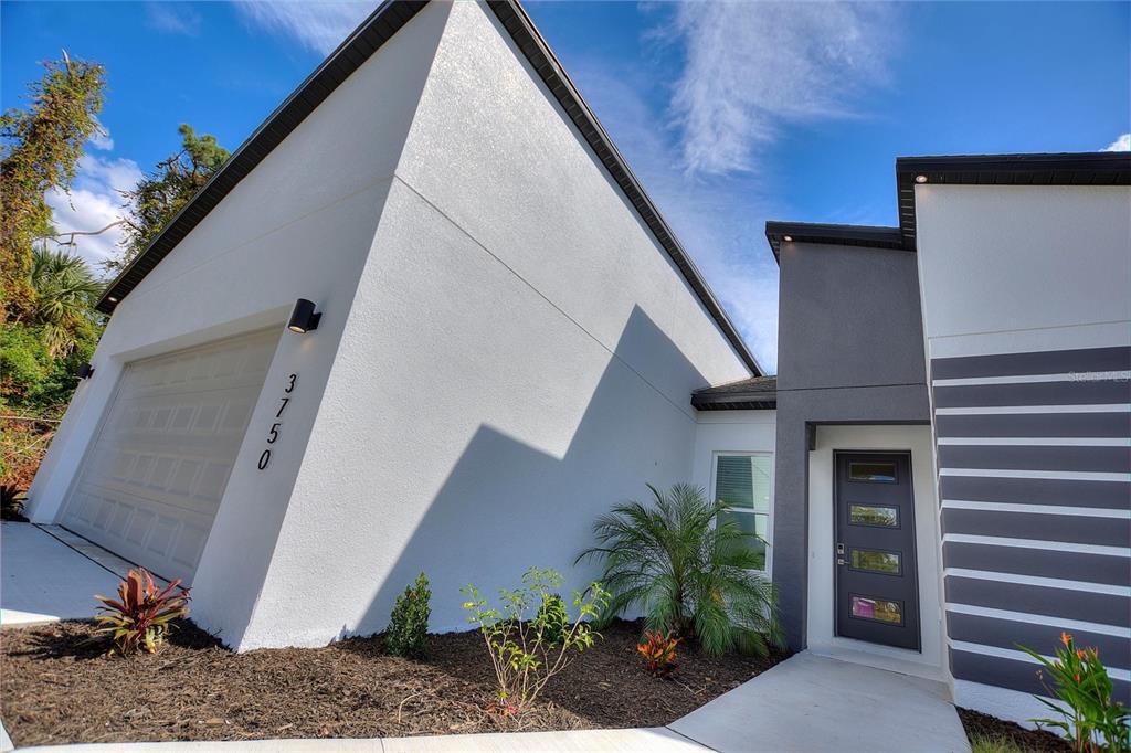 A modern home exterior features a white garage, a gray entryway, and a concrete walkway — 3707 FONTAINEBLEAU STREET, NORTH PORT, FL