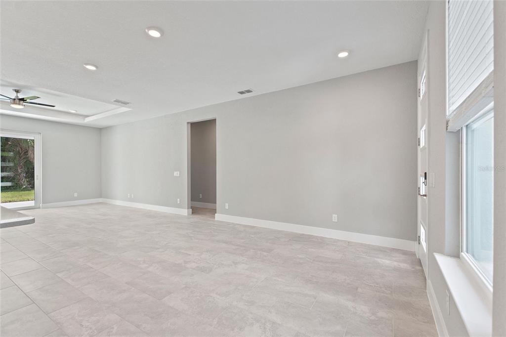 A bright, empty living room features light gray walls, tile flooring, recessed lighting, and a doorway — 3707 FONTAINEBLEAU STREET, NORTH PORT, FL