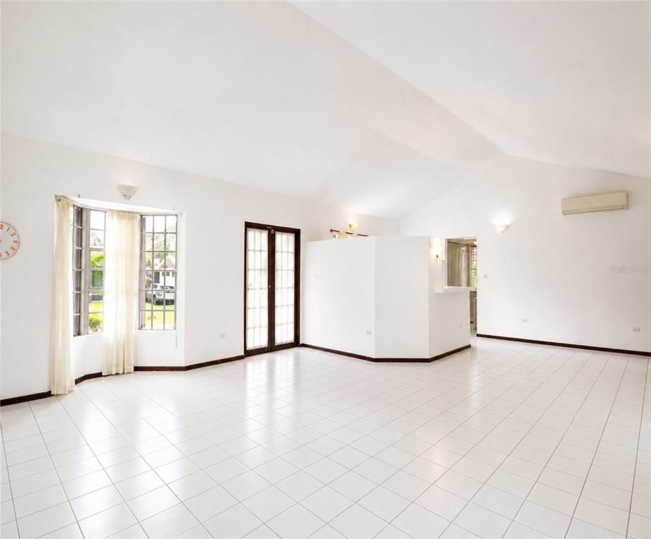 A bright, empty living room features white tile floors, vaulted ceilings, and a bay window — 160 CAMINO DE LAS POMARROSAS URB. HACIENDA SABANERA, CIDRA, PR