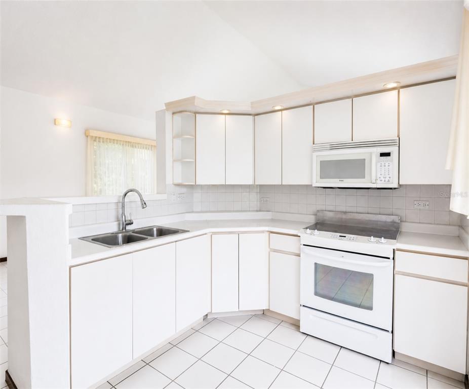 A kitchen with white cabinets, white appliances, a double sink, and white tiled flooring — 160 CAMINO DE LAS POMARROSAS URB. HACIENDA SABANERA, CIDRA, PR