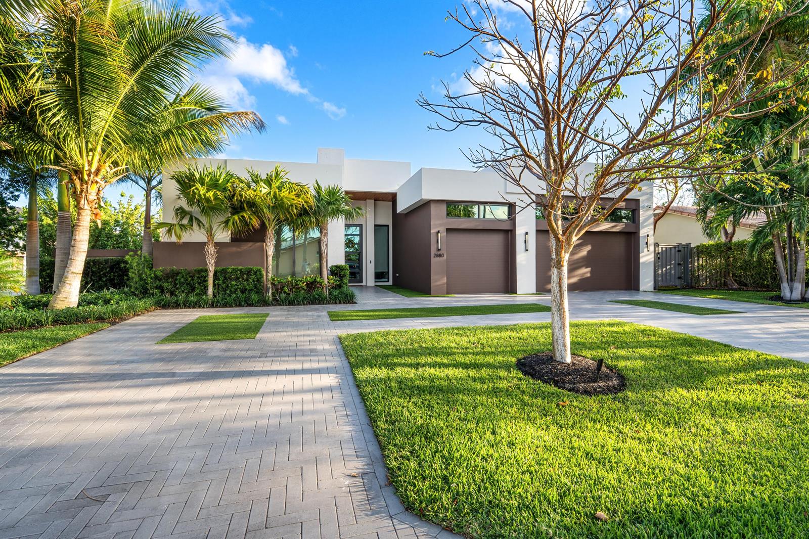 A modern single-story house with a brown and white exterior, palm trees, and paved driveway — 2880 NE 35th Street, Lighthouse Point FL 33064, LIGHTHOUSE POINT, FL