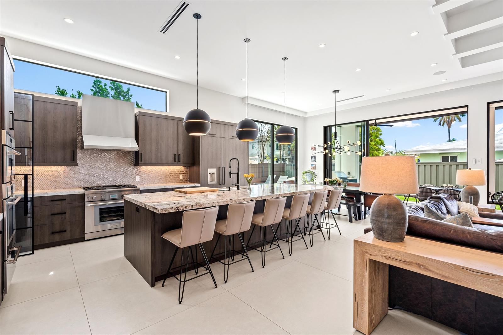 A modern kitchen features dark wood cabinetry, a large stone island, and an open living area — 2880 NE 35th Street, Lighthouse Point FL 33064, LIGHTHOUSE POINT, FL