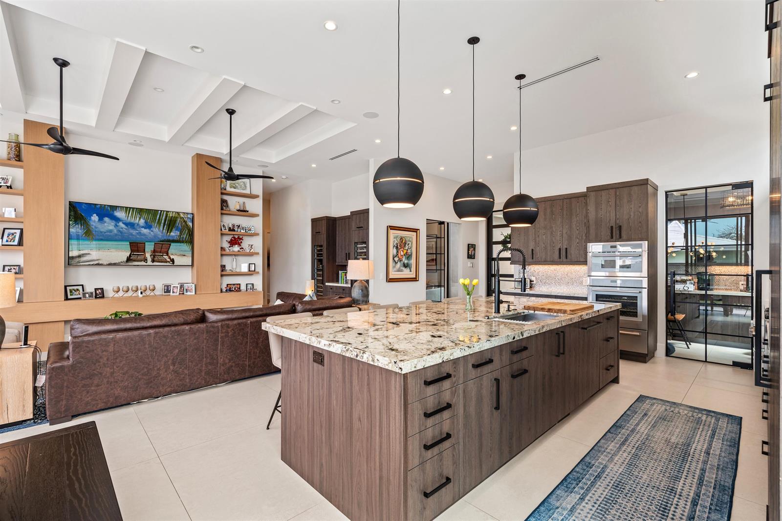 A modern open-concept kitchen and living area featuring a large granite-topped island and dark cabinetry — 2880 NE 35th Street, Lighthouse Point FL 33064, LIGHTHOUSE POINT, FL