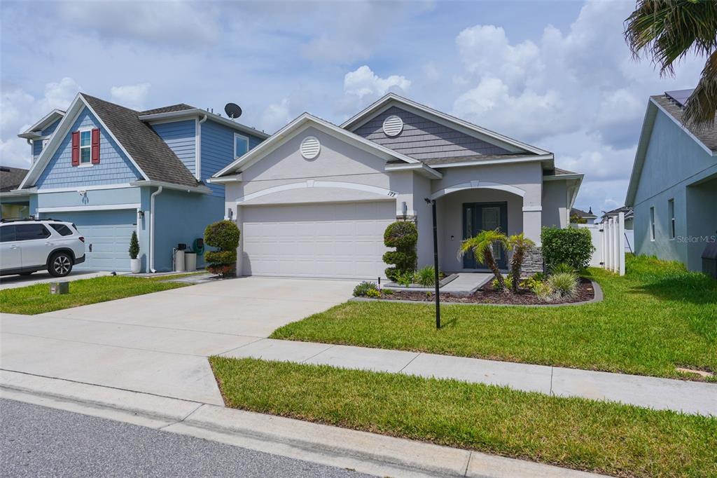 A single-story house with a beige stucco exterior, a two-car garage, and a landscaped yard — 173 VILLAVISTA COURT, DAVENPORT, FL